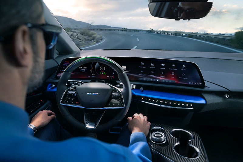 Front View of the 2026 OPTIQ-V Driving Through the Dusk Utilizing its Headlights | Cadillac of Greenwich in Greenwich CT